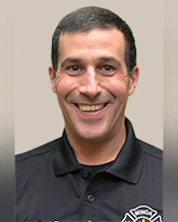 A smiling Brad Tygar wearing a black shirt with a Minoa FD logo.