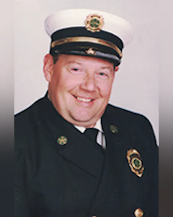 Al Tompkins in a formal uniform with a hat and badge, smiling.