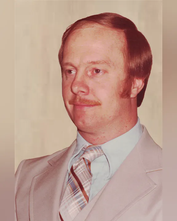 Jack Robie with red hair, mustache, light suit, blue shirt, and striped tie.
