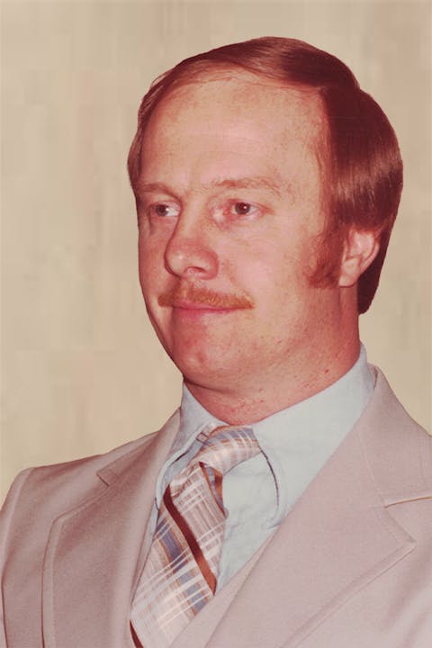 Jack Robie with red hair, mustache, light suit, blue shirt, and striped tie.