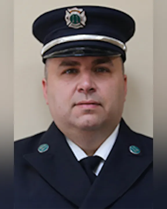 Nick Carulli in a formal dark uniform and cap, with badges visible.