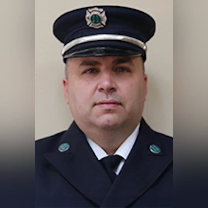 Nick Carulli in a formal dark uniform and cap, with badges visible.