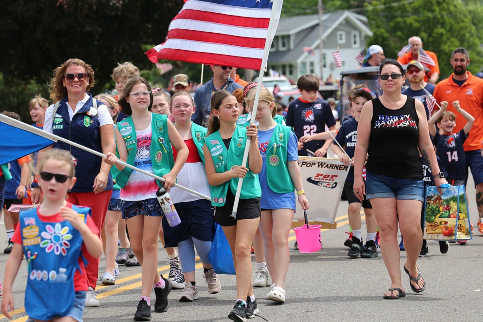 Young Girl Scouts march in the parade and wave the American flag.