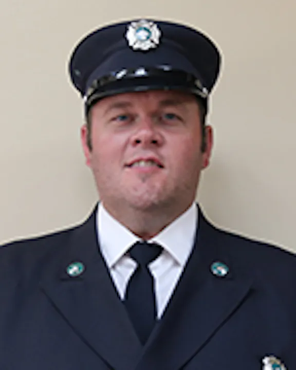 Robert Becker in a firefighter's uniform with badges on the chest.