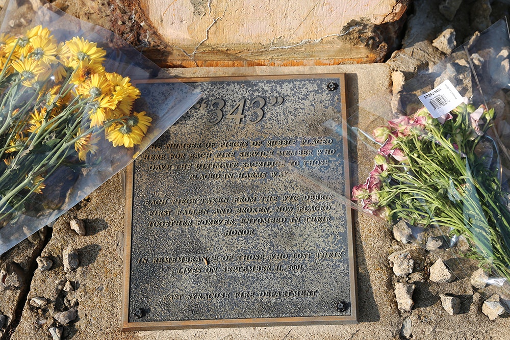 A memorial plaque with "343" atop and flowers beside it, honoring service members who perished on September 11, 2001.