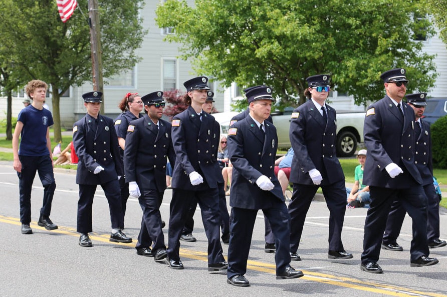 A group of Minoa Fire Department firefighters marching in uniform during the parade.