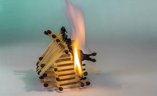 A small house made of matchsticks on fire.