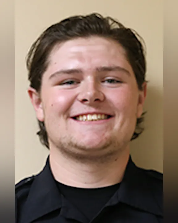 A smiling Aaron Reynolds in a black, collared shirt.