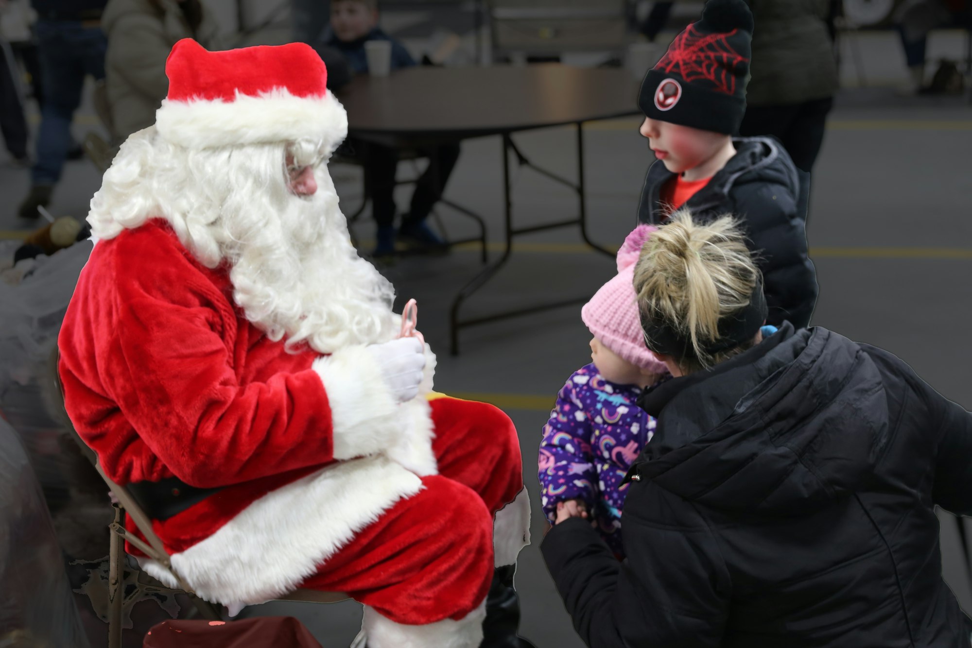 A man dressed as Santa Claus interacts with two children and an adult in a festive setting.