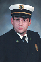 Matthew McGarrity in a uniform with a white hat and badge, a fire officer, against a neutral background.