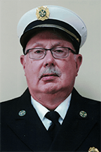 Pat Flannery,  in a white hat and dark uniform with badges, posing for a formal portrait.