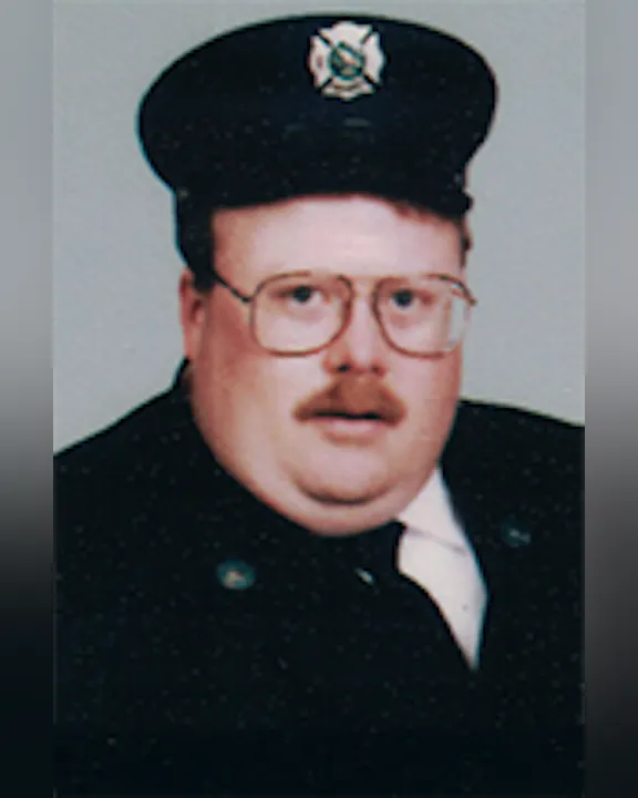 John abbott wearing a uniform, glasses, and a cap with an emblem.