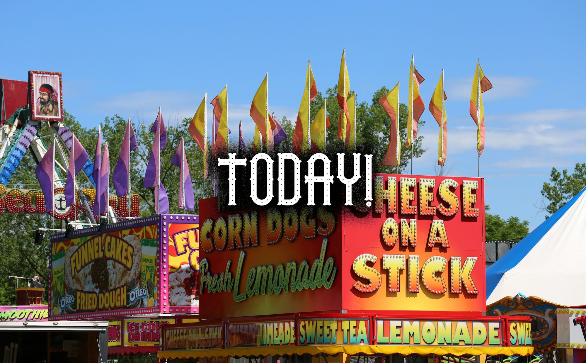 Colorful fairground stands with flags and signs for food, like corn dogs and funnel cakes, under a blue sky.