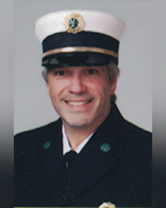 Randy Capriotti, Sr. smiling, wearing a uniform and a hat with a badge.