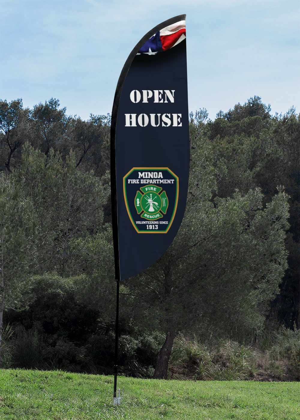 An "OPEN HOUSE" feather banner for a fire department, outdoors on grass with trees in the background.