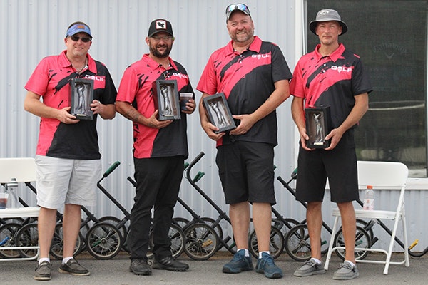 The four men, in matching pink shirts, who were on the second place team, holding awards.