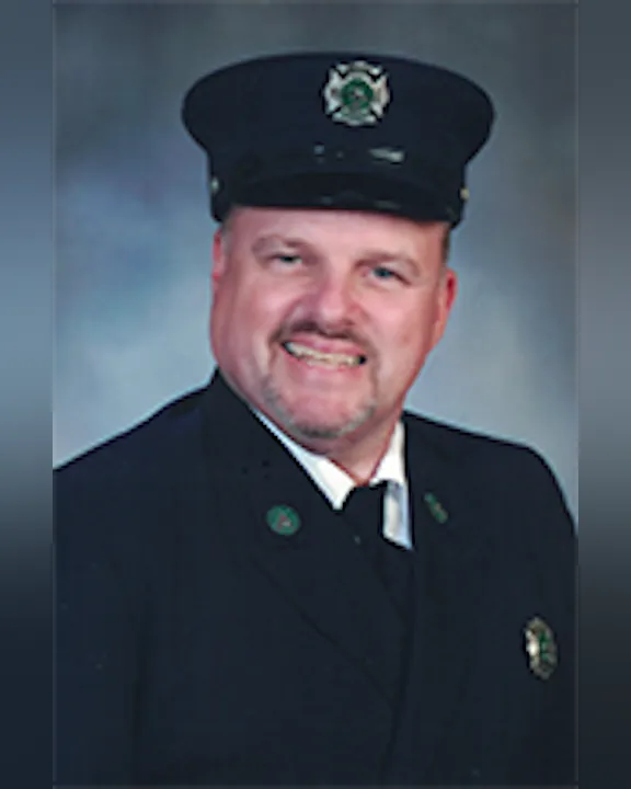 Tom Czajak wearing a formal uniform with a cap, smiling at the camera.