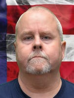 Portrait of Chuck Mullane in front of a US flag.