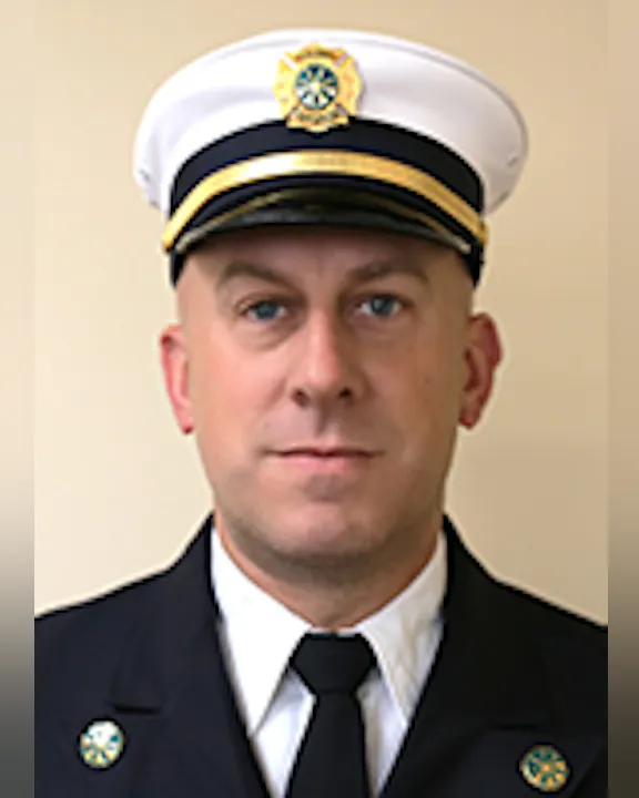 The image features a person in a formal uniform, wearing a cap with insignia, likely representing a fire or emergency service.