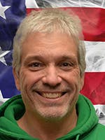 Portrait of Randy Capriotti, Sr. in front of a US flag.