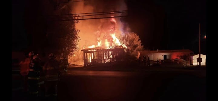 A building ablaze at night with firefighters on scene.