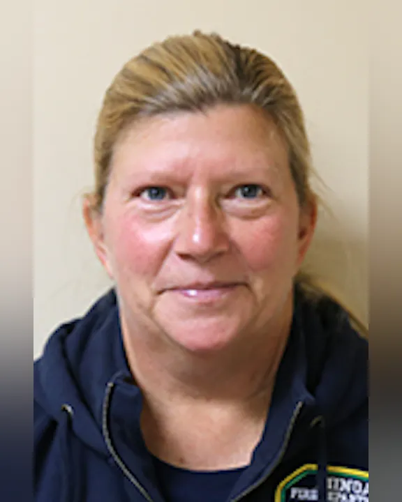 A smiling Tammy Maule with short hair wearing a dark jacket with the Minoa FD emblem.