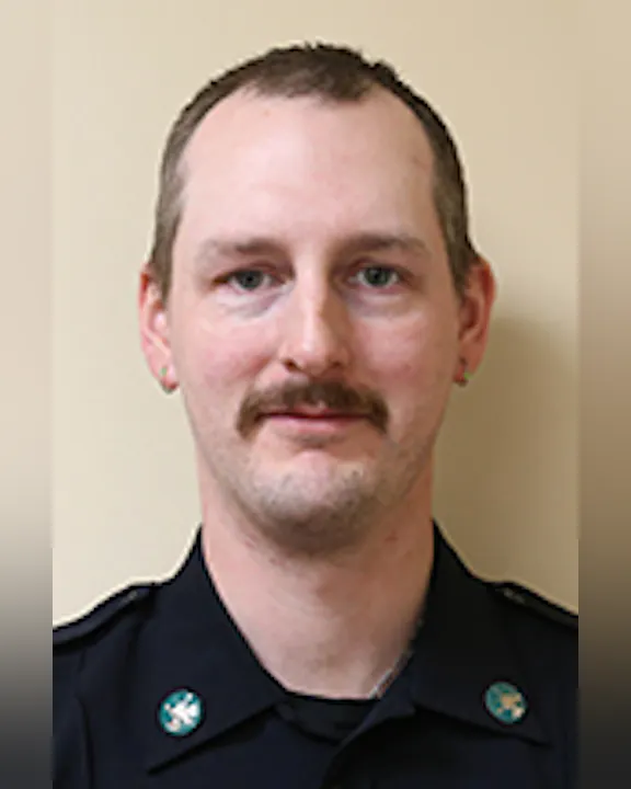 Matt Allen-Jennings wearing a dark uniform with badges, against a plain light background.