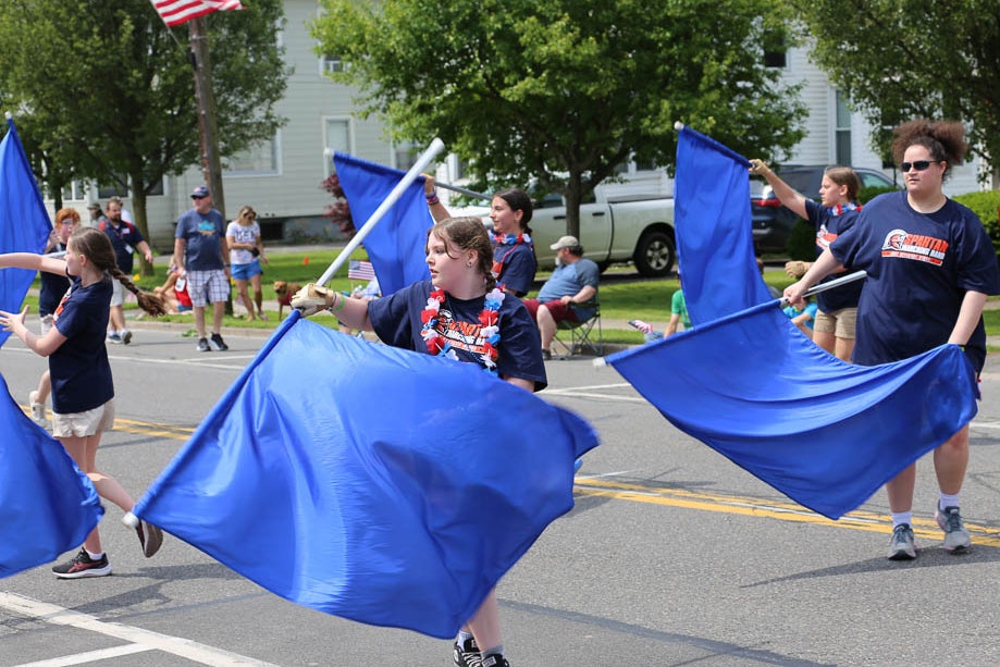 high school students festively wave blue flags as they parade.