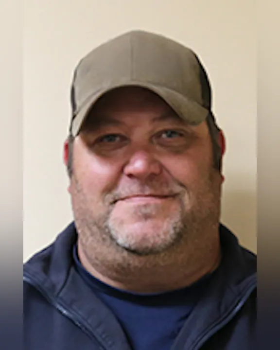 A smiling Jamie Maule with a cap and jacket against a plain background.