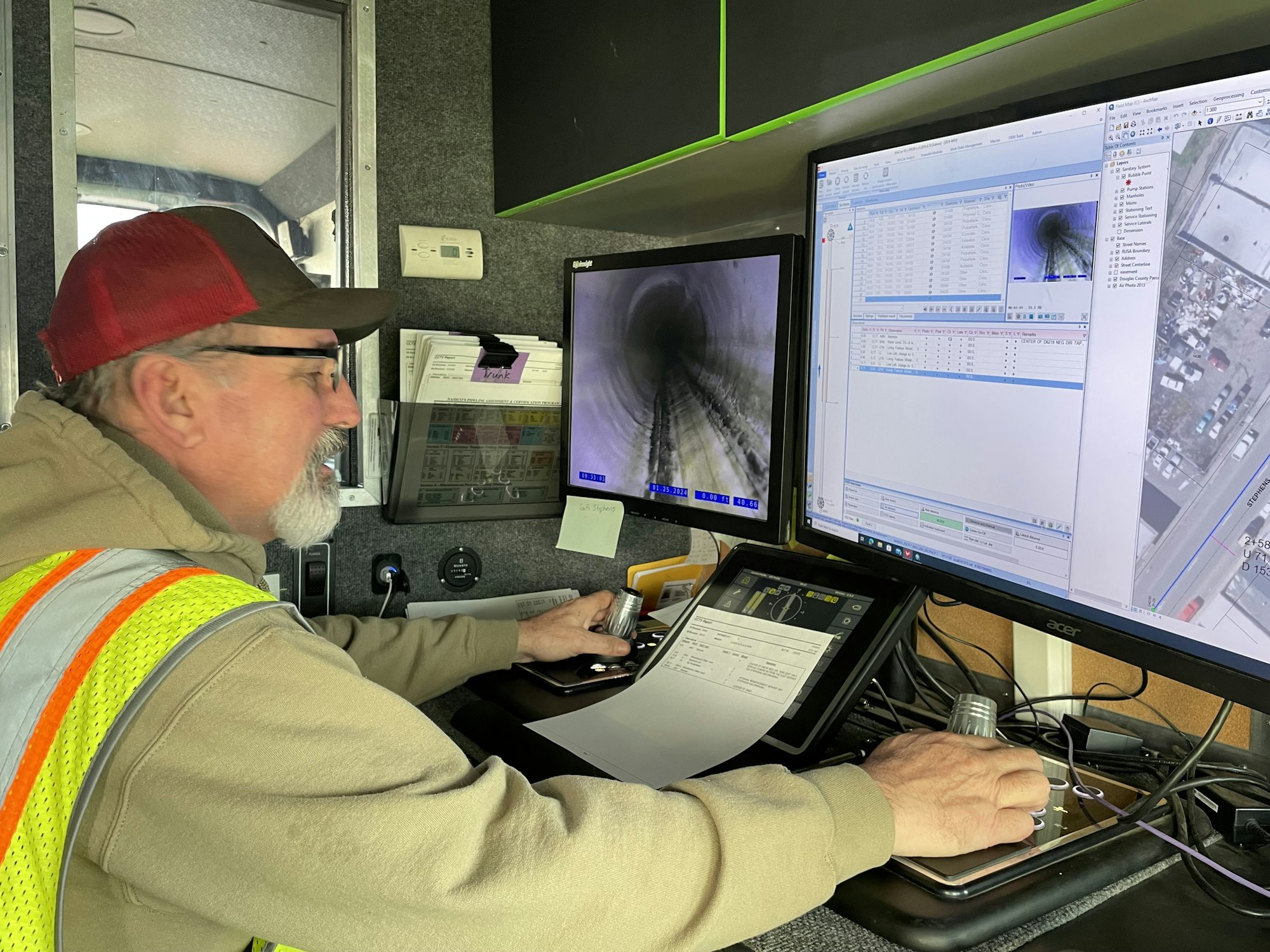 A person analyzing data and images on multiple computer screens inside a vehicle.