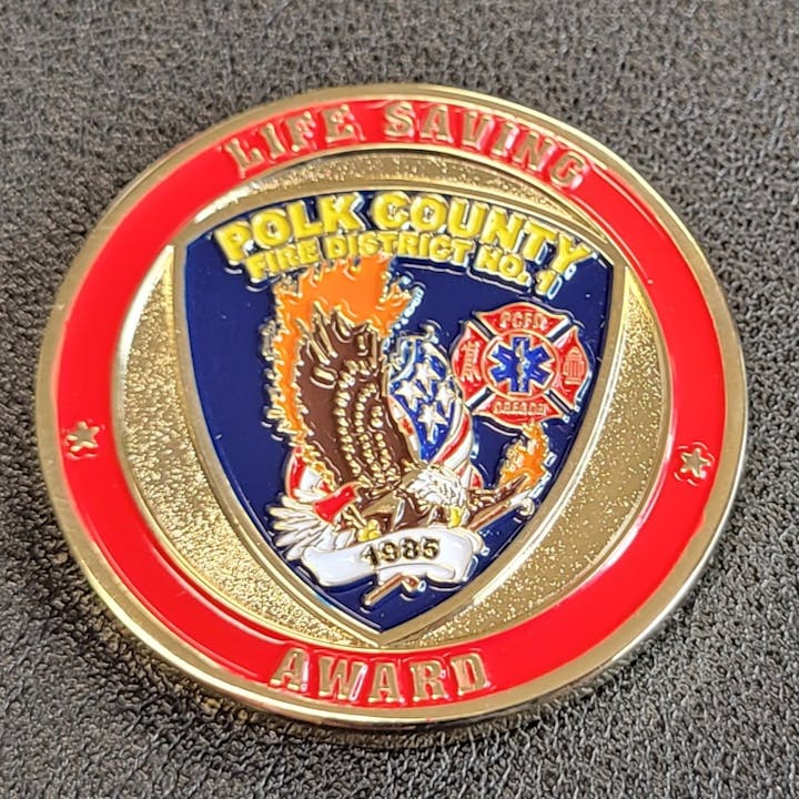 A Polk County Fire District No. 1 Life Saving Award coin with emblems and "Oregon" text.