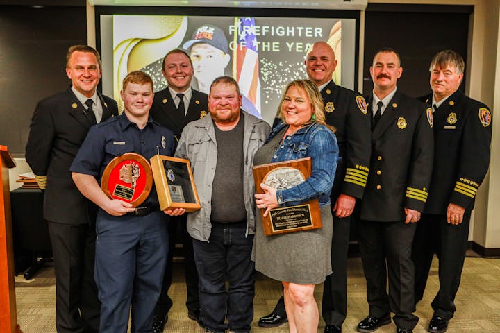 Group of people celebrating "Firefighter of the Year" with awards.