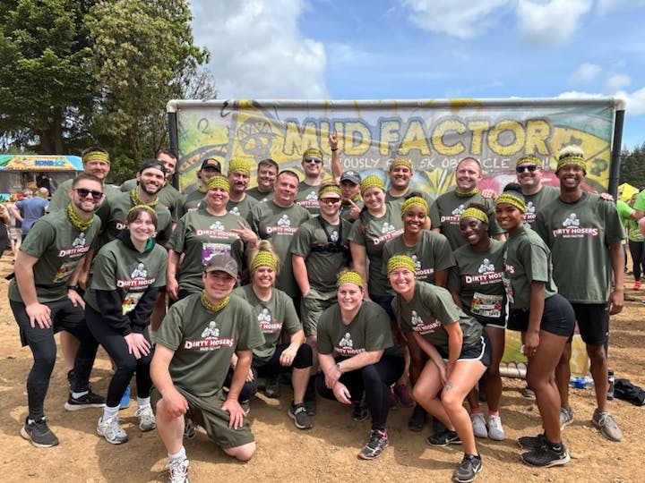 A group of people in matching t-shirts and headbands posing for a photo at a mud run event.