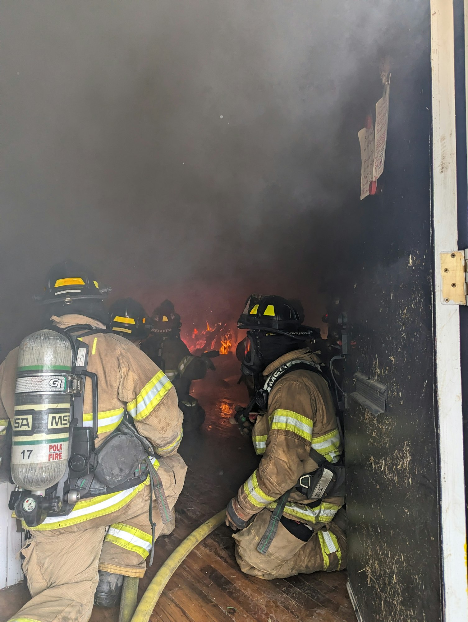 Firefighters tackling a blaze inside a smoke-filled room.
