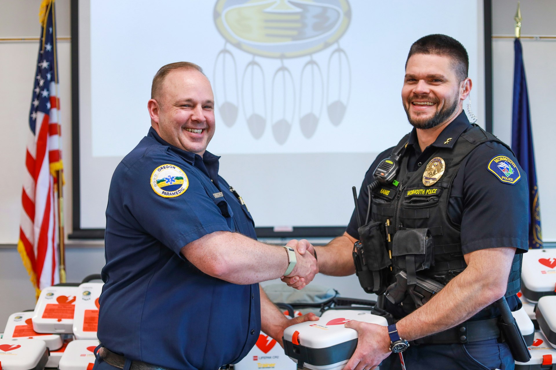 Firefighter and police officer shaking hands holding an AED