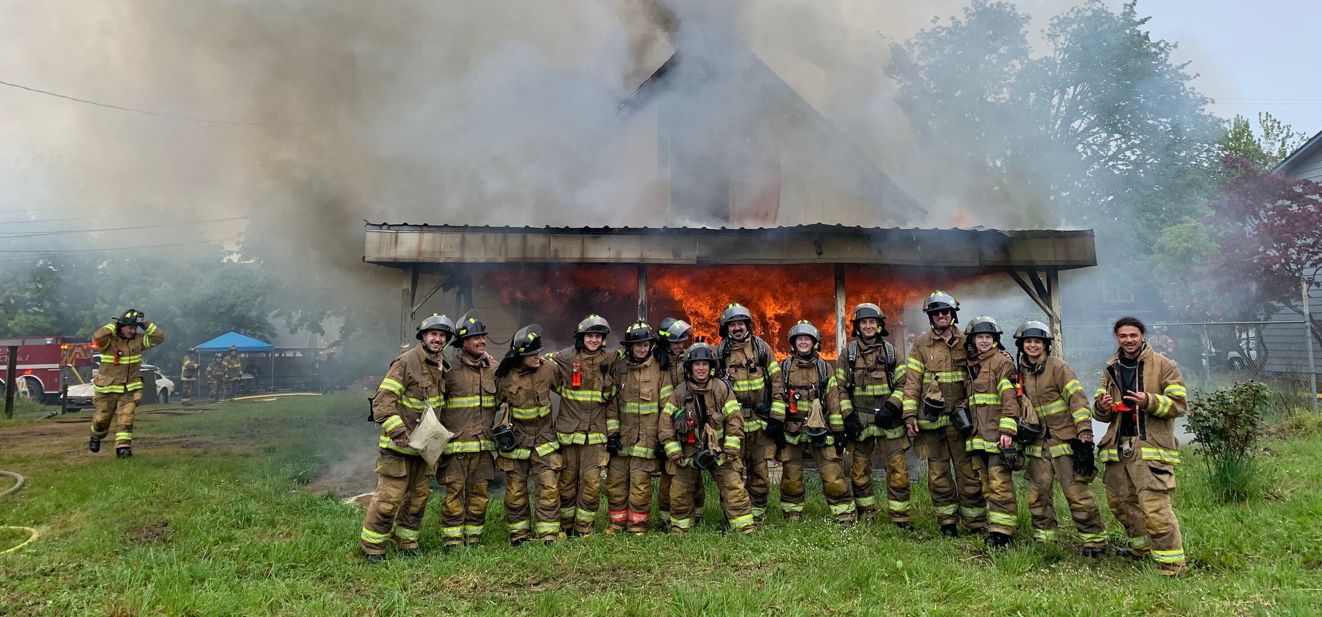 Group of firefighters in front of a burning house.