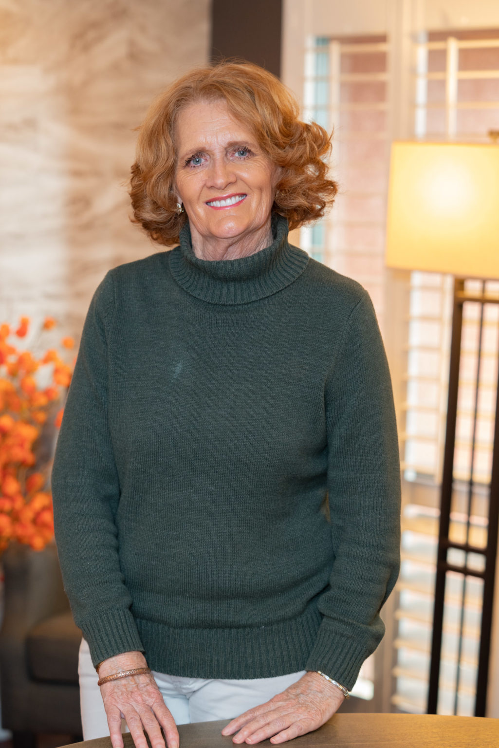 Image description: A photograph of Anne Trebino, smiling, with shoulder-length wavy red hair, wearing a grey sweater.