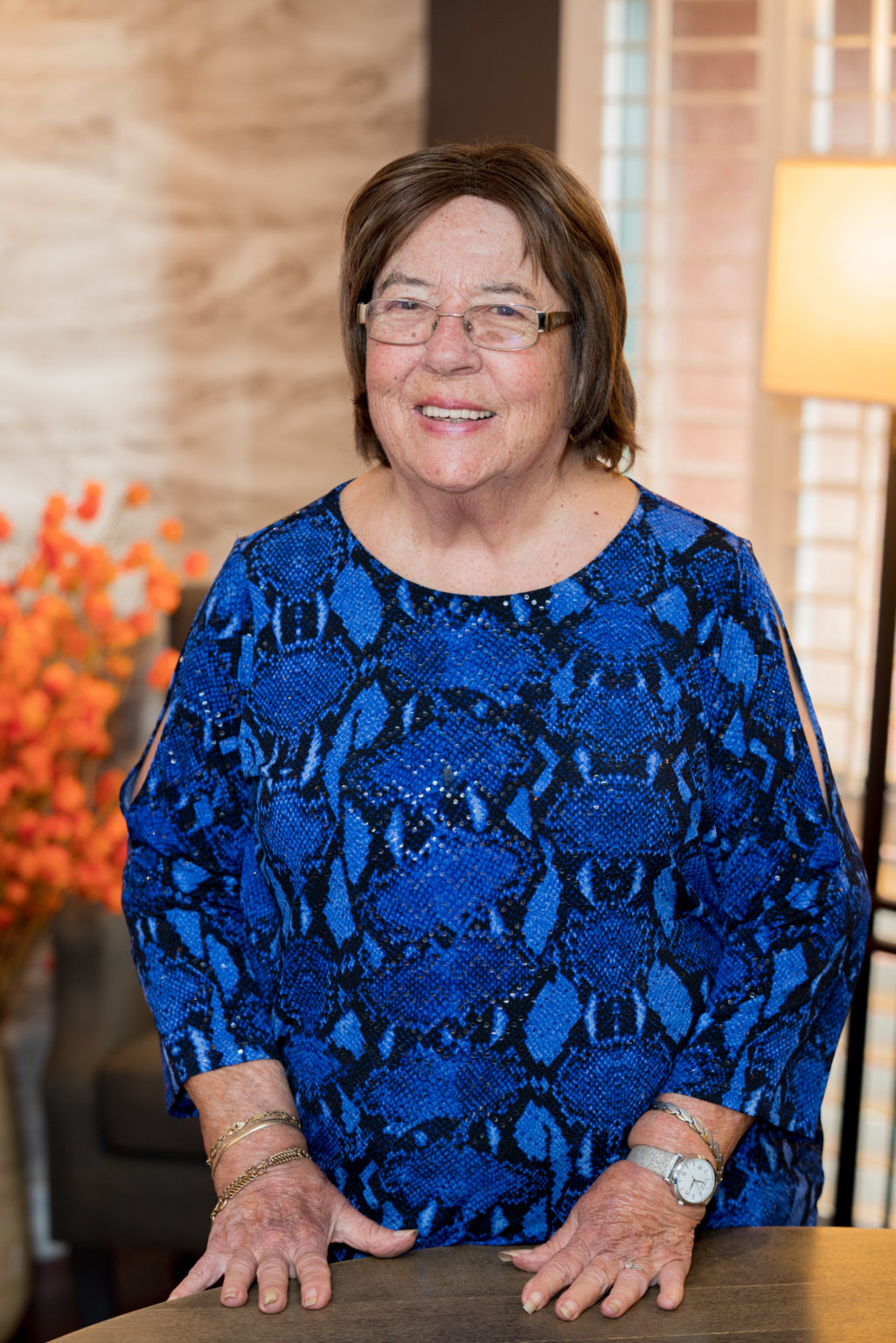 Image description: A photograph of Rosemary Guidotti, smiling, wearing glasses with short brown hair, and dressed in a blue and black patterned blouse.
