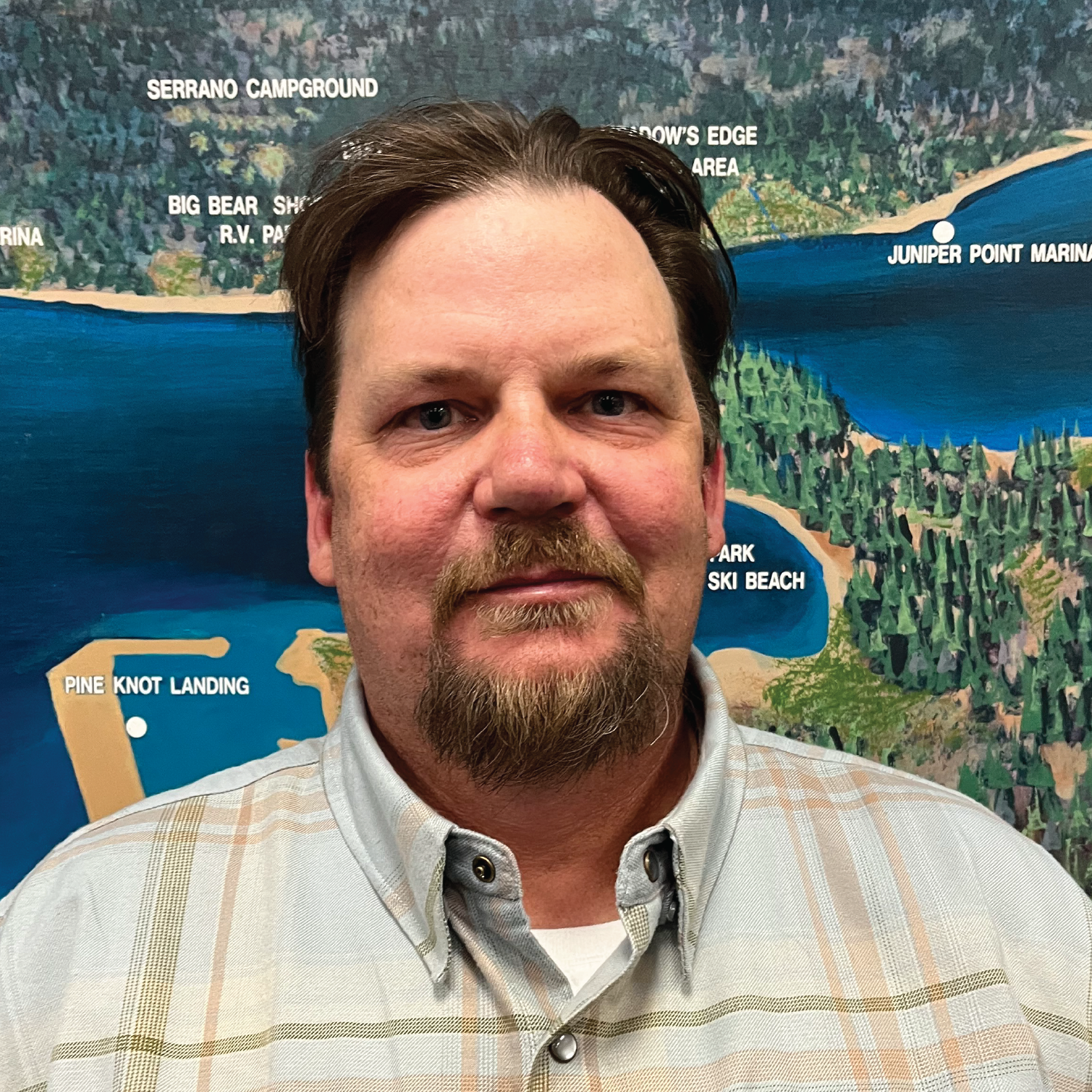 A man in front of a map showing places like "Serrano Campground" and "Big Bear Marina."