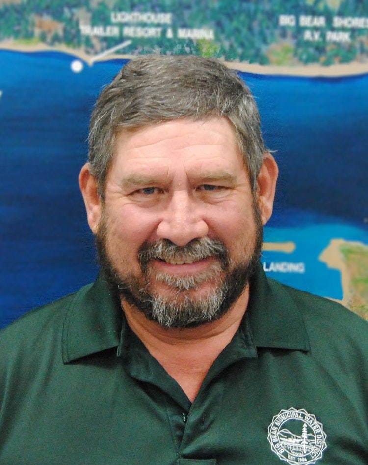 A smiling man in a green shirt with a map background.