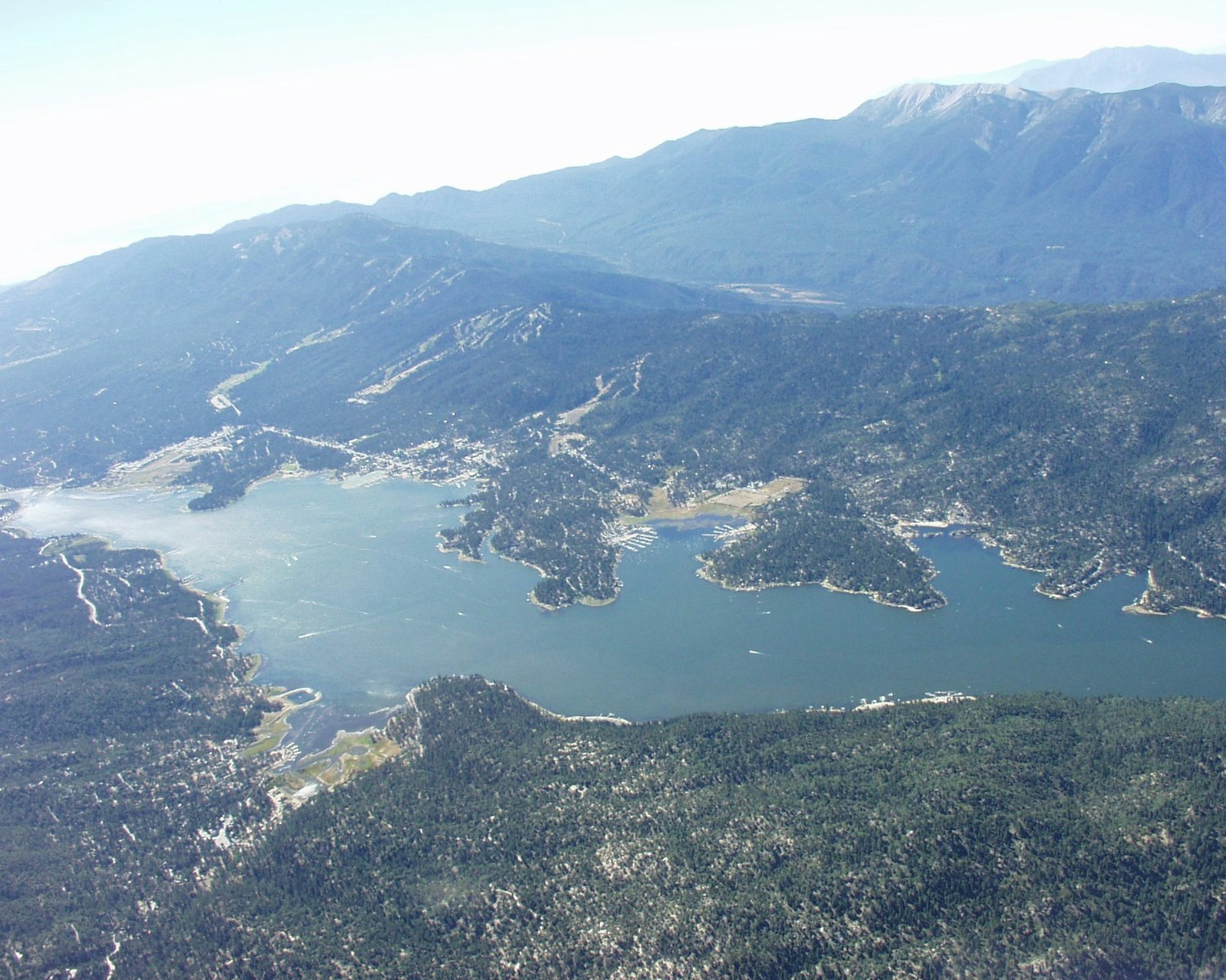 Aerial view of a mountainous region with a lake and forested areas.