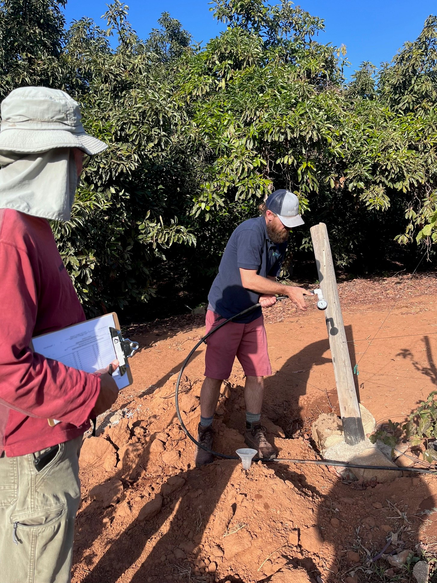 Two people conducting outdoor research or fieldwork in a treed area with equipment.