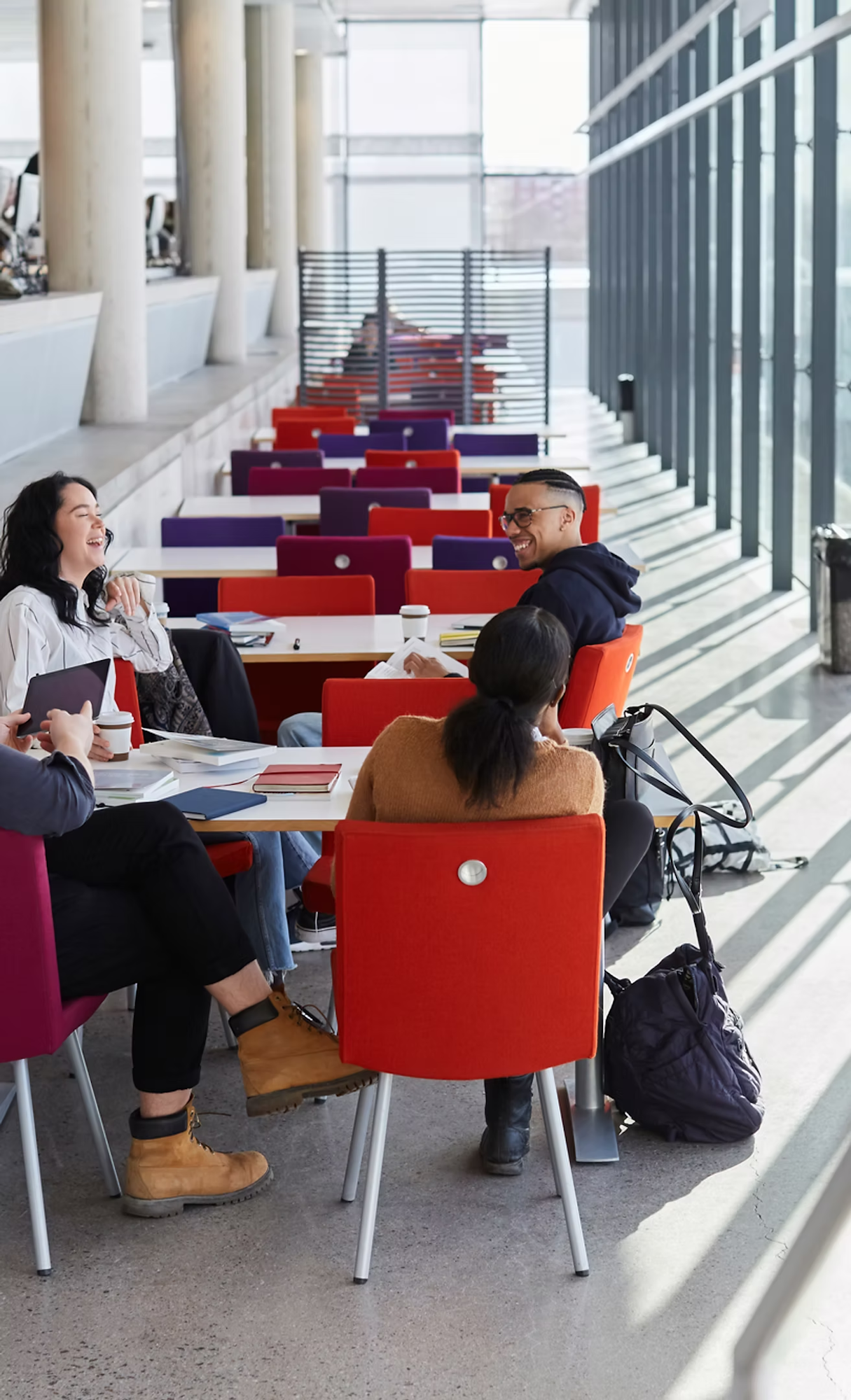 A group of people sitting at a table in a bright, modern setting, chatting and laughing.