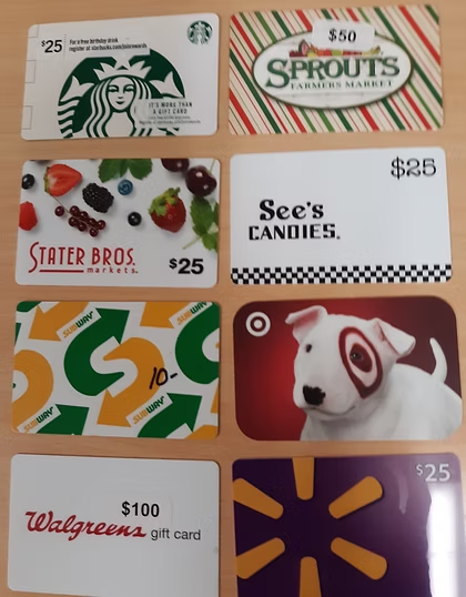 Various gift cards for Starbucks, Sprouts, Stater Bros, See's Candies, Subway, Target, Walgreens, and Walmart displayed on a table.
