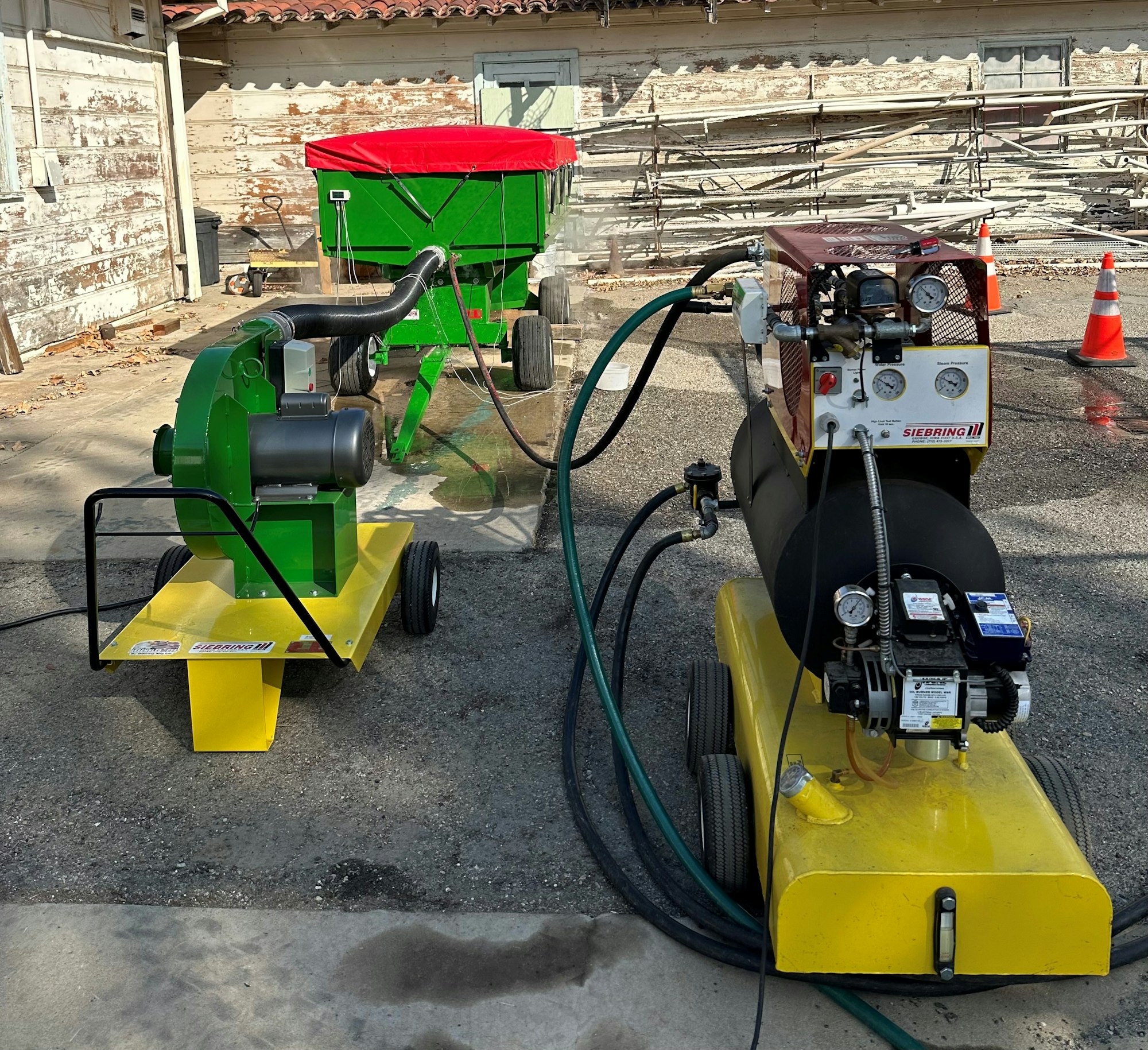 Green and yellow machinery with hoses and gauges, parked outdoors on a driveway.