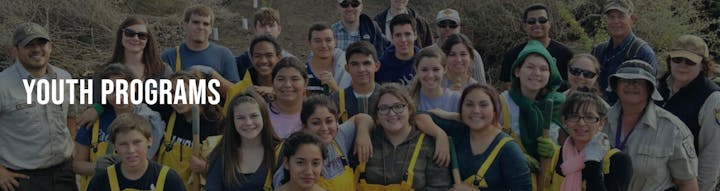 Group of people smiling outdoors, part of a youth program.