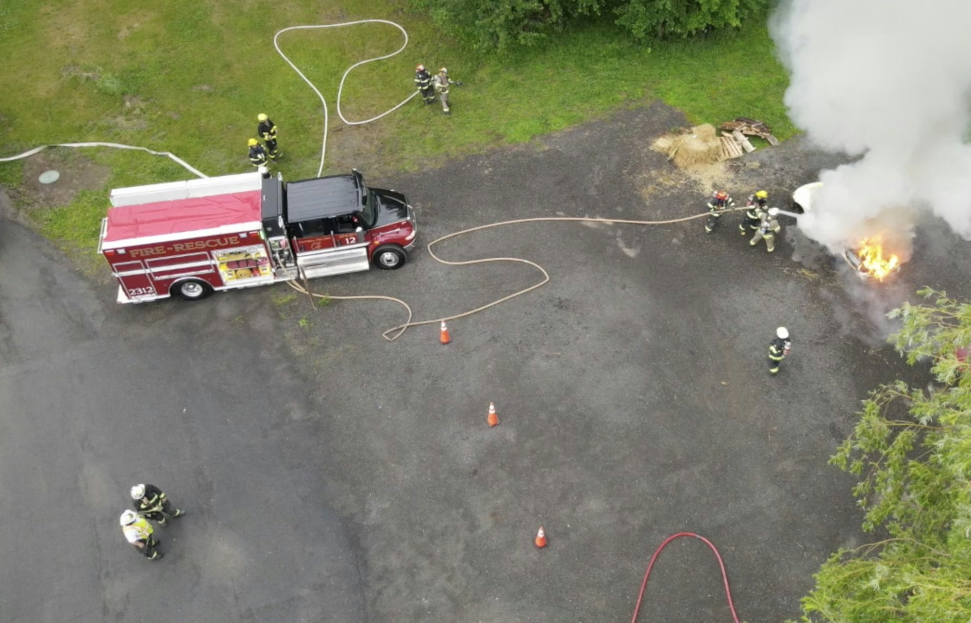 Aerial view of firefighters tackling a blaze near a fire-rescue vehicle.
