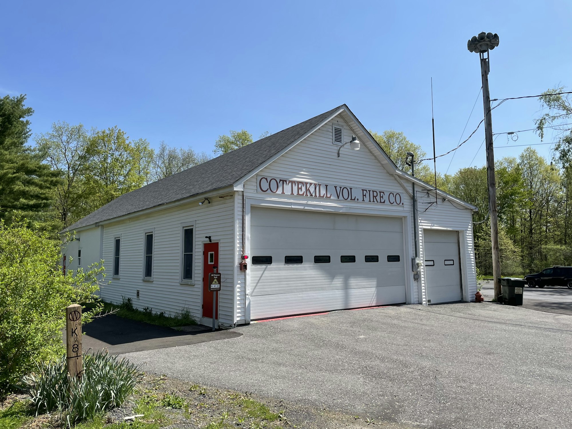 A volunteer fire company building with three garage doors, a clear sky, and surrounding greenery.