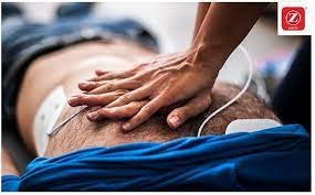 A person performing CPR, hands compressing chest, with a training defibrillator pad visible.