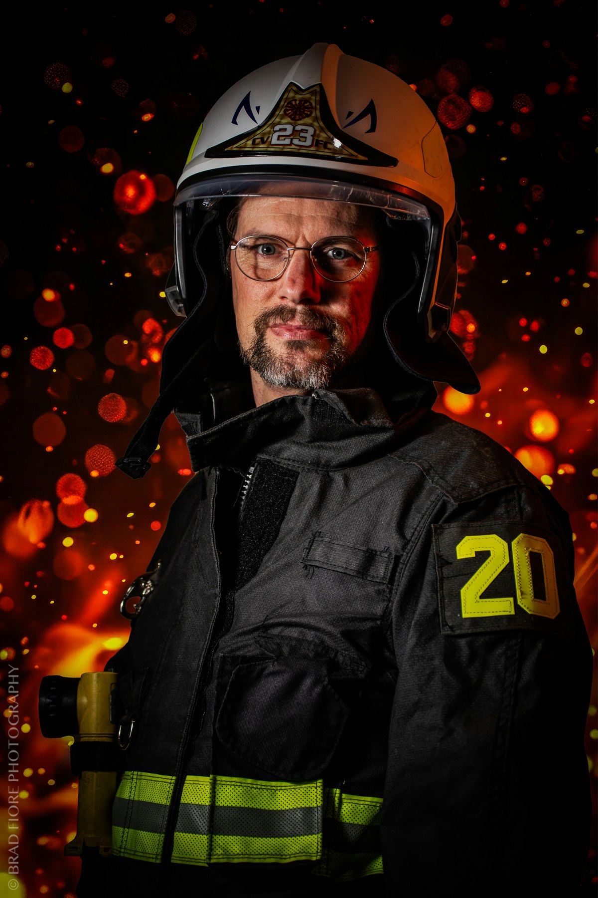 A firefighter in uniform with a helmet, against a fiery background with glowing orange bokeh lights.
